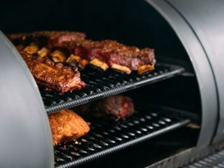 Close up of poultry and beef in a BBQ smoker